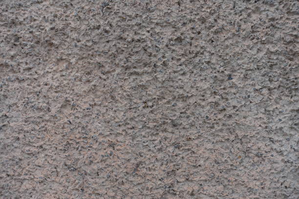 Uneven surface of gray wall with unpainted cement roughcast finish