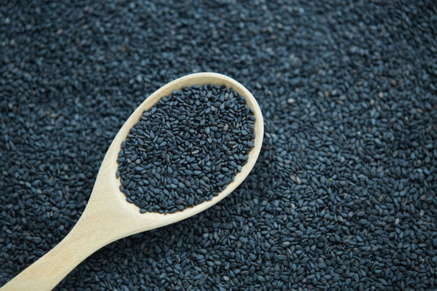istock Black sesame seeds in wooden spoon on black background 2173078499