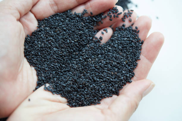 istock Black sesame seeds in female hand on white background 2173078510