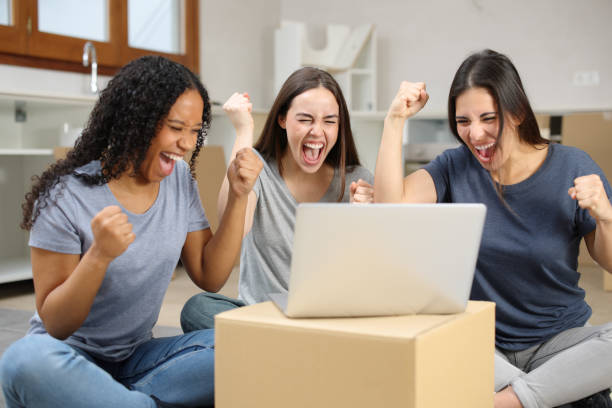 istock Three excited roommates celebrating checking laptop moving home 2173082301