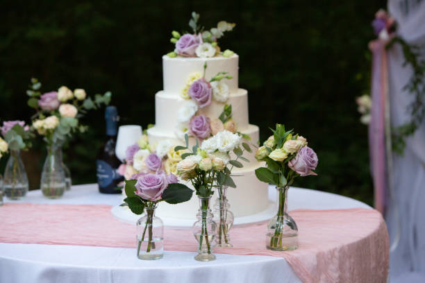 istock Wedding cake decorated with roses and eustoma flowers standing on table outdoors 2173085324