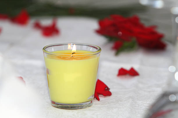 Yellow scented candle is burning on a table, creating a romantic atmosphere