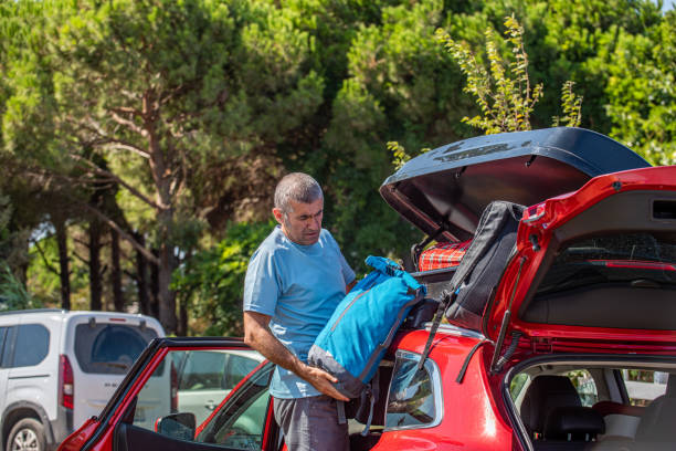 istock A father loading camping gear into the closed trunk of his car 2173085729