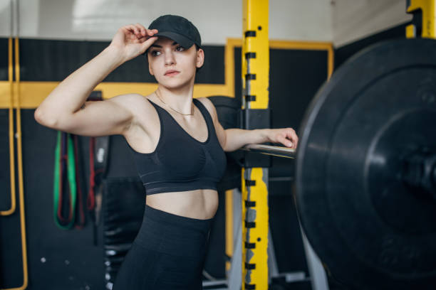 istock Young woman at gym adjusts cap before weightlifting 2173086963