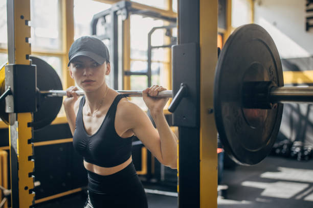 istock Athletic woman executing squats with gym barbell. 2173087380