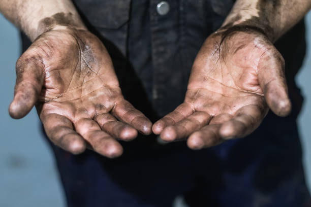 Anonymous mechanic showing dirty hands in car workshop