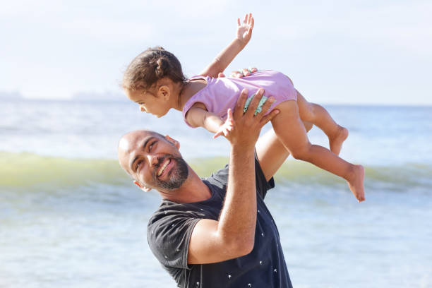 istock Father lifting daughter on beach 2173093101
