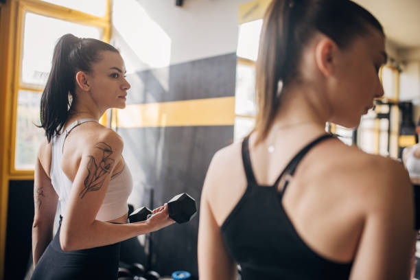 istock Woman lifting dumbbell in the gym, side view pose. 2173094040