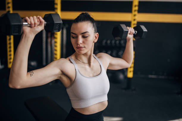 istock Woman lifting dumbbells in gym with focused expression 2173094080