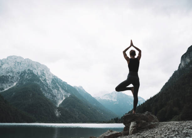 istock Young woman is practicing yoga at mountain lake. 2173094438