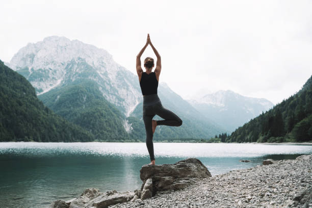 istock Young woman is practicing yoga at mountain lake. 2173094511