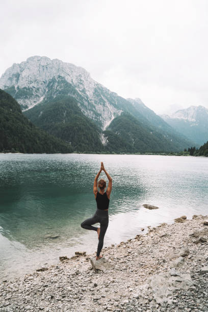 istock Young woman is practicing yoga at mountain lake. 2173094805