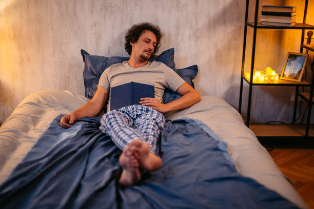 istock Mid-Adult Man Falling Asleep While Reading A Book In The Bed At Night 2173096918