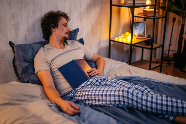 istock Mid-Adult Man Falling Asleep While Reading A Book In The Bed At Night 2173097144
