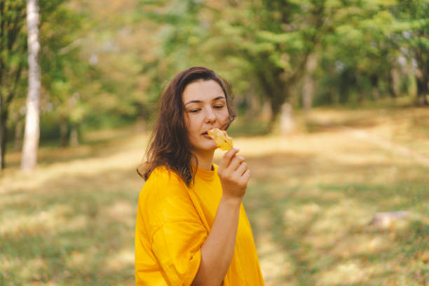 istock A woman enjoys a autumn day while playfully holding a yellow leaf 2173097291