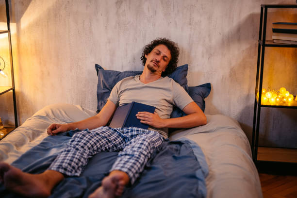 istock Mid-Adult Man Falling Asleep While Reading A Book In The Bed At Night 2173098210