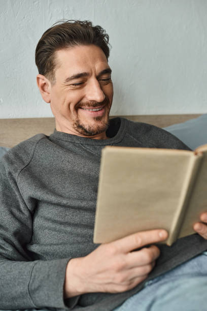 istock Cozy afternoon at home with a handsome man enjoying a book and relaxing on a comfortable bed 2173103706