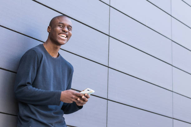 istock Happy black man using smartphone against gray wall 2173112491