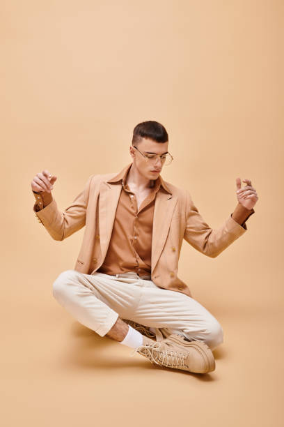 Stylish man captivating the spotlight with confident pose against a warm peach backdrop