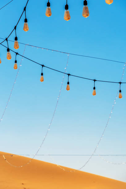 istock String lights hang against a clear blue sky, with a sandy desert dune 2173113500