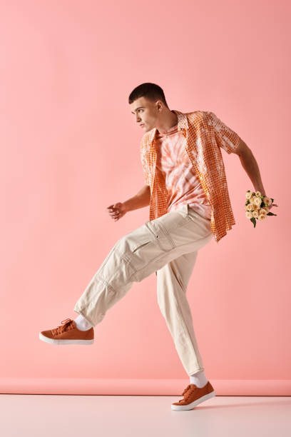 istock A stylish young man joyfully strikes a pose against a vibrant pink backdrop while holding flowers 2173113683