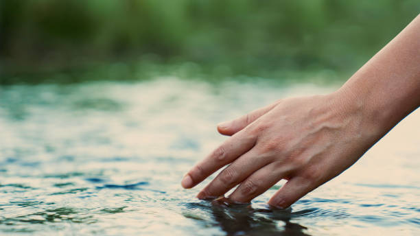 istock A female hand touching the river water 2173116143