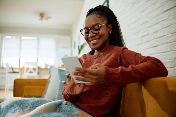 istock Happy black woman using smart phone while relaxing at home. 2173118637