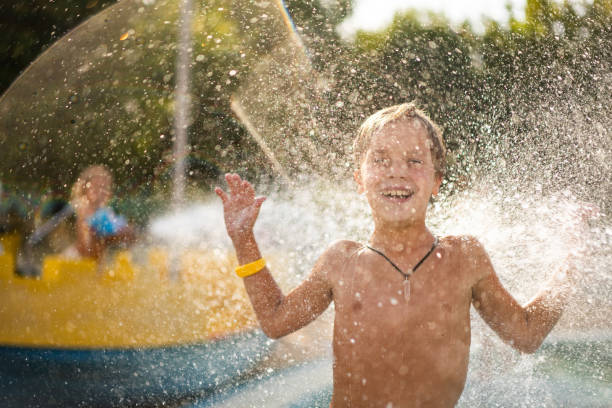 Joyful little boy having fun in water park at summer day