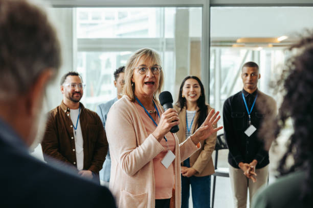 istock Confident female speaker leading a training session with engaged employees in a modern office environment, promoting professional growth and team building 2173130220