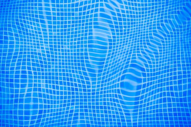 Gentle ripples and reflections create a captivating pattern in the blue tiled water of a swimming pool.