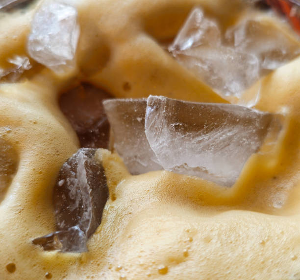 Ice sitting in and on top of frothy ice coffee