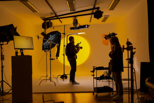 istock Videographer in film studio with vibrant yellow background 2173155105