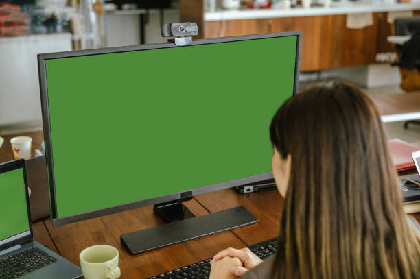 istock Online Meeting : Young Woman Sitting at Her Desk Using Desktop Computer with Mock-up Green Screen 2173158079