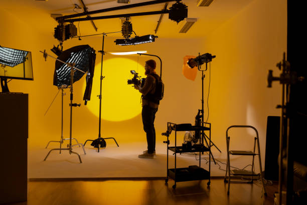 istock Videographer in film studio with vibrant yellow background 2173158136