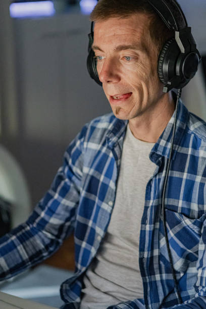 istock Relaxed middle-aged man with headphones playing video games at home on a computer. 2173170660
