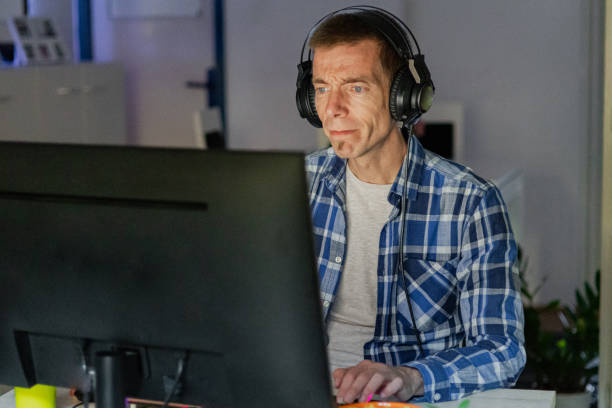 istock Relaxed middle-aged man with headphones playing video games at home on a computer. 2173170873