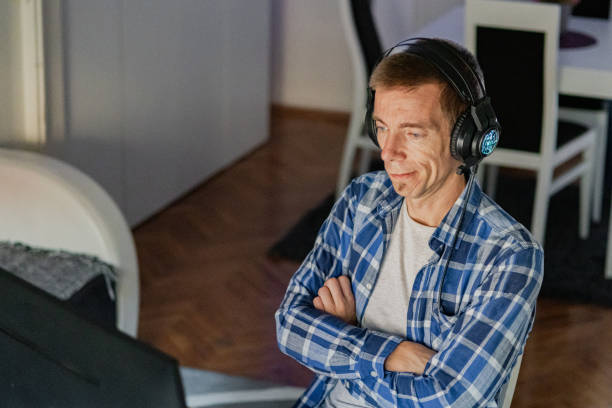istock Relaxed middle-aged man with headphones playing video games at home on a computer. 2173172707