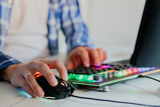 Close-up of man's hands while playing computer games with rgb computer keyboard and mouse.