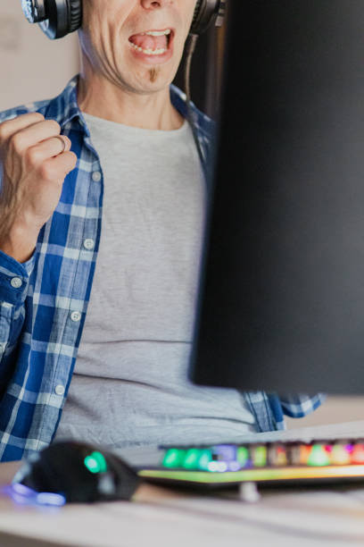 istock Relaxed middle-aged man with headphones playing video games at home on a computer. 2173173709