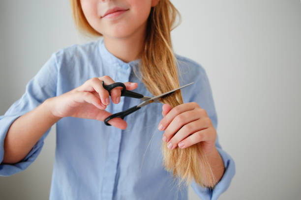 istock A girl cuts her long hair with scissors. 2173175797