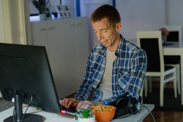 istock Relaxed middle-aged man with headphones playing video games at home on a computer. 2173176109