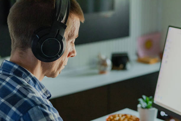 istock Relaxed middle-aged man with headphones playing video games at home on a computer. 2173176370