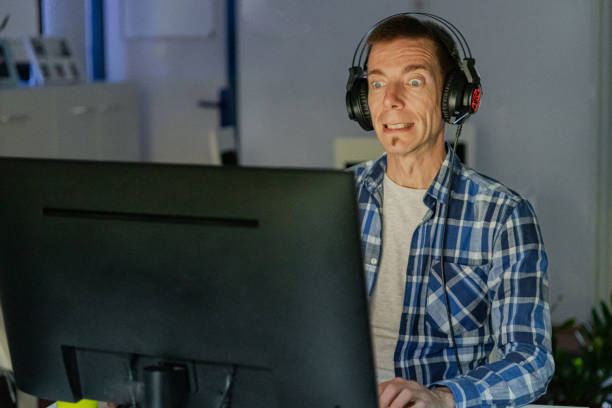 istock Relaxed middle-aged man with headphones playing video games at home on a computer. 2173176794