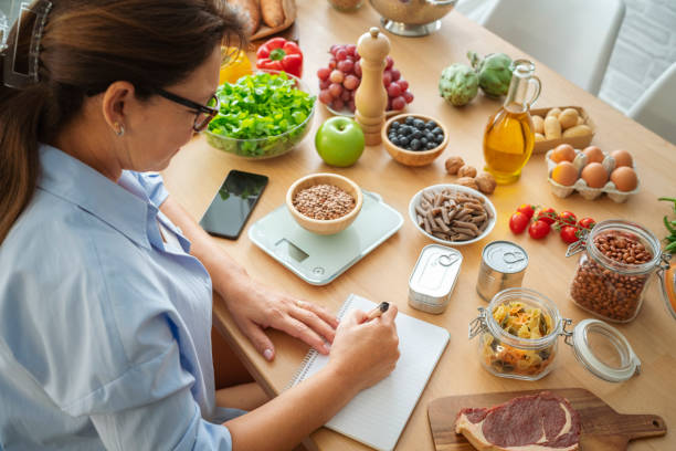 Woman planning, writing weekly meals on a meal planner note pad