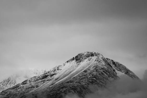 Long distance photograph of snowy mountain peaks with an overcast cloudy sky during winter