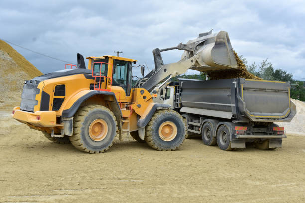 Yellow excavator loading rocks into a truck in a quarry