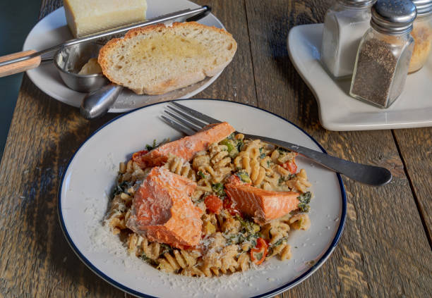 A white plate of salmon fillet grilled pasta fine dining restaurant