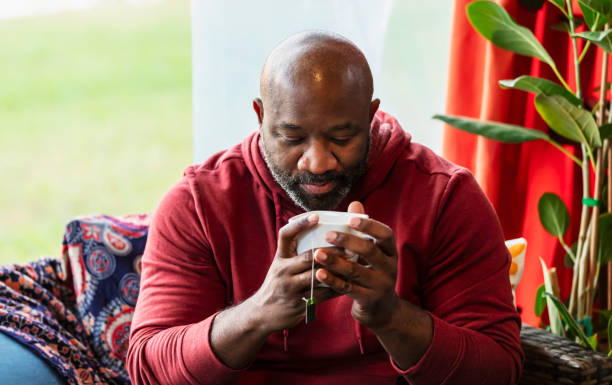 Serious multiracial man looks down into cup in hands, calm