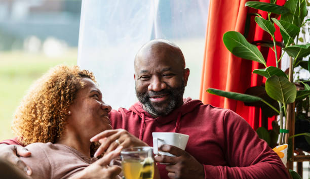 istock Mature couple relaxing on sofa, drinking tea, smiling 2173201528