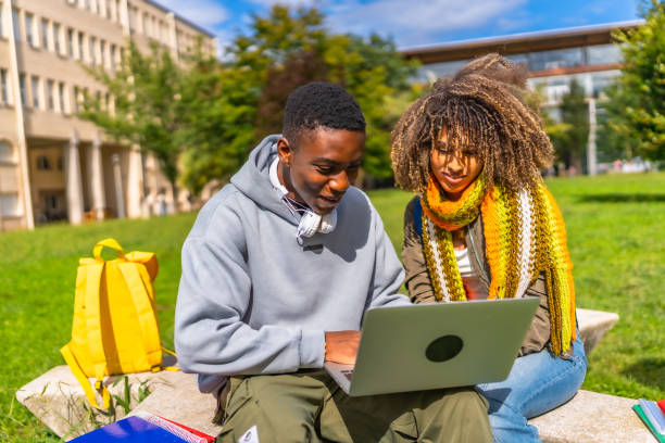 istock African student and colleague using laptop sitting outside the campus 2173208828